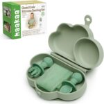 A haakaa Cloud Crew 5-piece green silicone baby travel feeding set with a foldable plate, bib, spoon, fork, and travel bag.