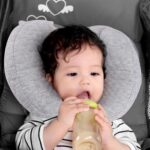 Light grey KAKIBLIN infant travel pillow with a heart shape, providing head and neck support for babies.