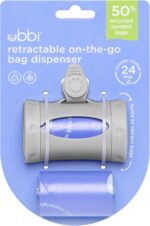 Gray retractable diaper bag dispenser with a roll of lavender-scented bags, clipped to a stroller handle.
